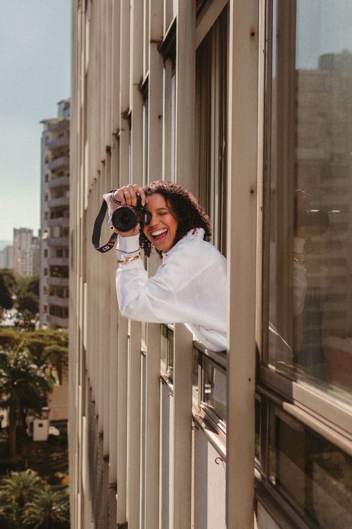 Isadora Hadassa fotografando debruçada na janela